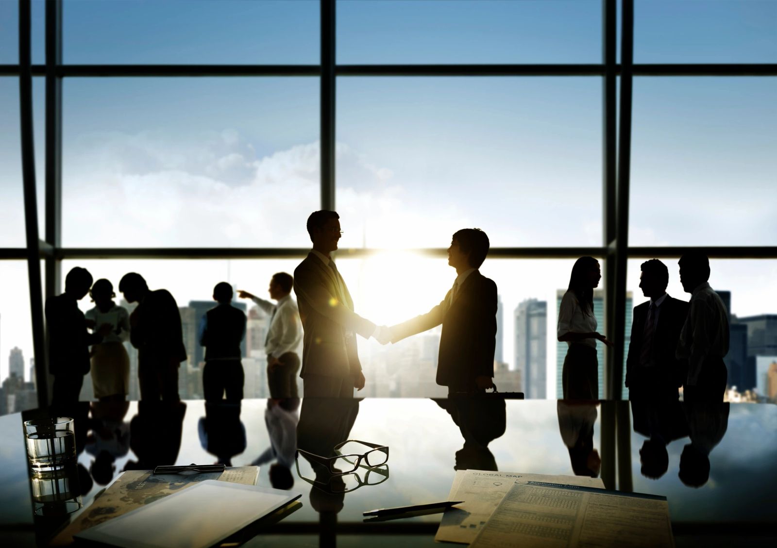 Business professionals shaking hands in office with city view.